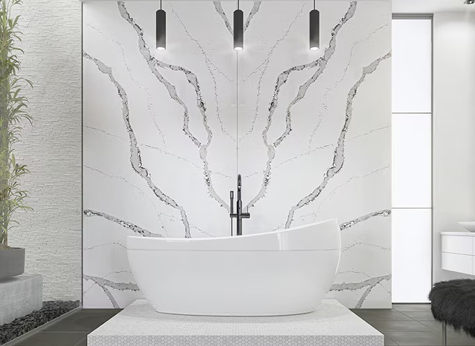 Quartz slab wall in a white Calacatta look behind a freestanding tub